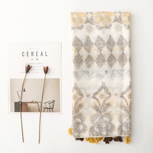 Ethnic bohemian scarf with yellow geometric floral patterns and tassels on white background