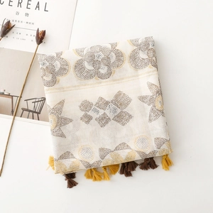 Flat-lay detail of bohemian scarf with floral dot patterns and elegant tassel fringes
