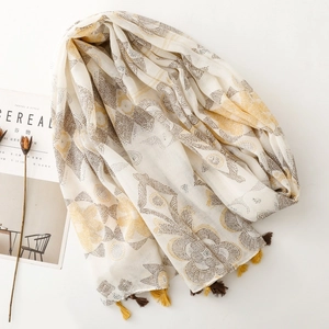 Detail of ethnic floral scarf with yellow tassels and minimalist magazine background