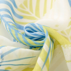 Gros plan sur un tissu léger à imprimé feuilles tropicales montrant sa texture fluide