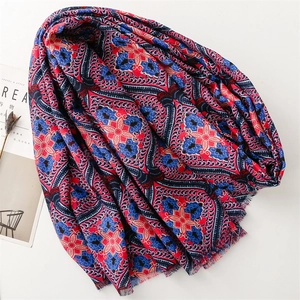 Détail d'une écharpe bohème aux motifs paisley rouges et bleus avec bords à franges