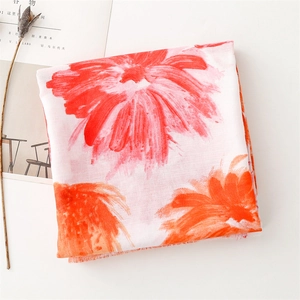 Detail of floral print scarf with orange and red patterns and delicate fringe edges