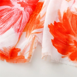 Close-up of orange floral print on breathable cotton-linen feel scarf with fringed edges