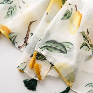 Detail of thin scarf featuring lemon prints and colorful tassels with a light texture