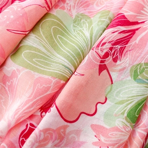 Close-up of pink linen-touch fabric with red floral prints and breathable texture