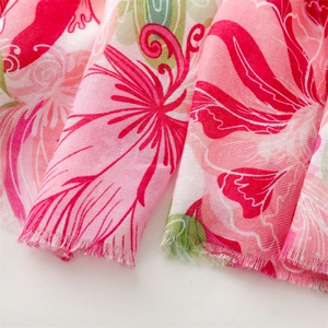 Macro shot of pink floral linen scarf featuring frayed edges and detailed herringbone texture