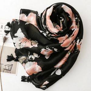 Détail d'une écharpe florale noire avec motifs de magnolia rose et pompons faits à la main