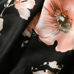 Gros plan d'un foulard floral avec fleurs roses sur tissu noir à chevrons