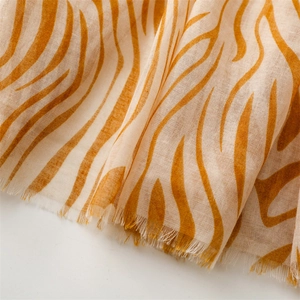 Detailed texture of lightweight zebra print scarf with frayed edges in mustard yellow