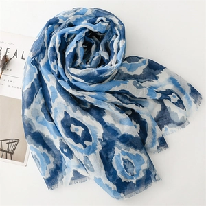 Flat lay of blue geometric watercolor scarf with fringe edges and magazine props