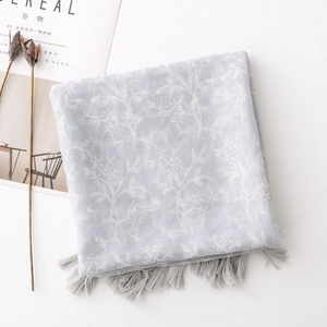 Detail of light blue scarf with white coral prints and grey tassel trim on white background