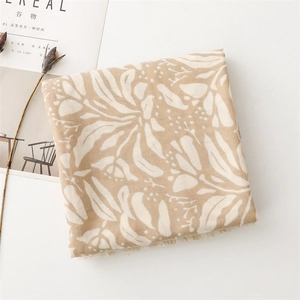 Macro detail of beige cotton linen scarf with floral leaf patterns and fringe edges