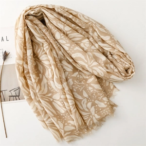 Detail of khaki cotton-linen scarf featuring white floral patterns and fringed edges