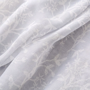 Close-up of elegant leaf floral embroidery on lightweight light gray voile scarf fabric