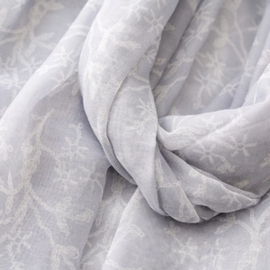 Close-up of lightweight light gray scarf with delicate white floral embroidery texture