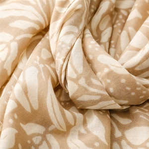 Close-up of tropical leaf print on soft linen-feel scarf with white polka dot detail