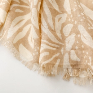 Detail of khaki linen-feel scarf showing elegant white botanical leaf print and frayed edges