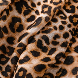 Close-up of lightweight leopard print scarf fabric showing soft fringe and breathable texture