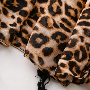 Close-up of leopard print sheer scarf fabric with delicate black fringe tassel detail