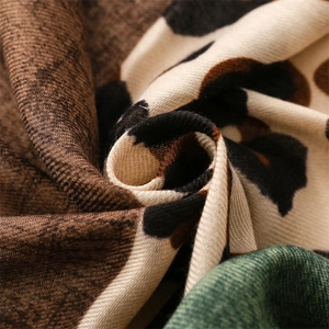 Close-up of green leopard print scarf fabric showing soft weave texture and fringe detail
