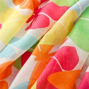 Detail of soft breathable fabric with vibrant carrot and floral prints and fine texture