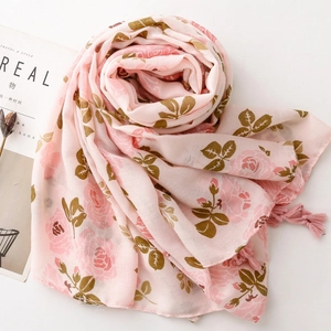 Détail d'une écharpe fleurie rose avec imprimé roses et bords à pompons délicats
