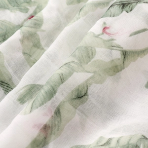 Detailed close-up showing light green tropical leaf print on soft breathable muslin fabric