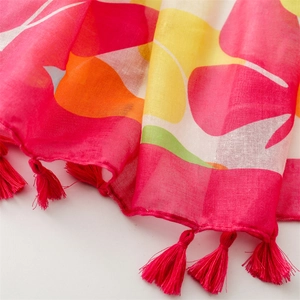 Close-up of vibrant floral print scarf fabric with colorful fringes and woven texture