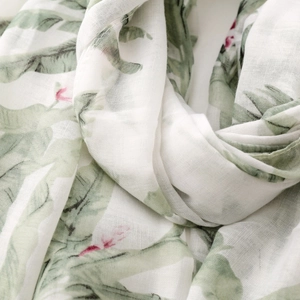 Detail of thin Bali yarn scarf with green tropical leaf prints and fringe texture
