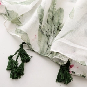 Detail of tropical green leaf print on thin voile scarf with dark green tassel fringe