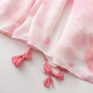 Detailed view of pink and white tie-dye fabric featuring soft tassels and fine texture