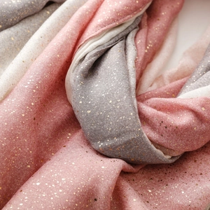 Detail of soft linen-feel scarf with gradient tones and shimmering gold foil speckles