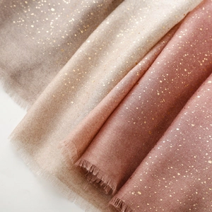 Detailed close-up of soft linen-touch scarves with gold foil dots and fringe edges