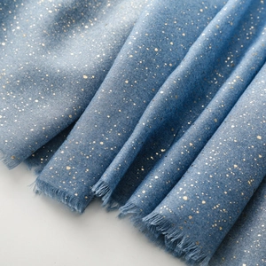 Detail of blue cotton-linen scarf featuring gold foil pattern and fringed edges