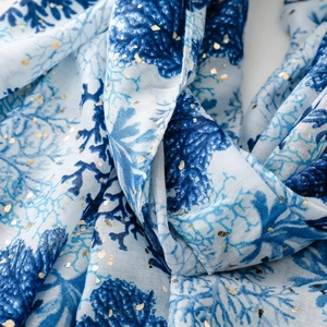 Detailed view of white cotton-linen scarf with blue coral reef pattern and gold foil accents