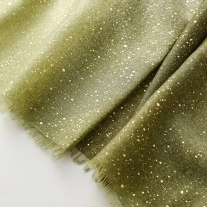 Detailed view of olive green scarf with gold foil splash and raw fringe edges