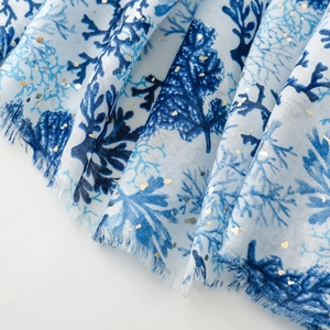 Macro detail of blue coral print scarf with gold foil accents and fringe edges