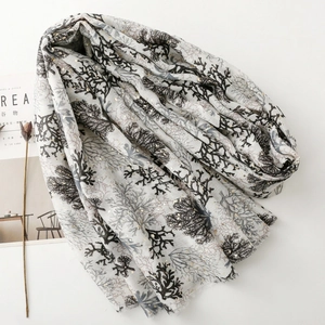 Detail of coral print scarf with gold foil accents and fringe edges on white background