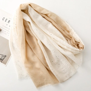 Detailed view of light beige linen scarf with gold foil dots and frayed fringe edges