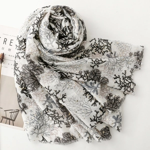 Detail of linen-feel scarf with coral prints, gold glitter accents and frayed edges