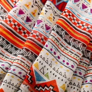 Detailed macro view of Bohemian geometric floral patterns on a colorful tassel shawl