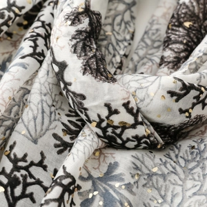 Close-up of coral branch print on linen-feel scarf with elegant gold foil detailing