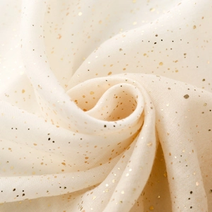 Detail of light beige cotton linen scarf featuring elegant gold bronzing and soft fringes