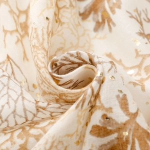 Macro detail of cotton-linen scarf with brown leaf prints and golden foil coral accents