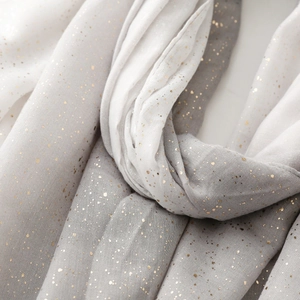 Detail of soft gradient scarf featuring metallic gold flecks on breathable linen fabric