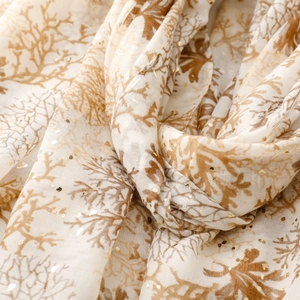 Detailed macro view of coral pattern print and golden foil on beige linen feel scarf