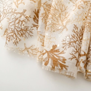 Detailed macro view of coral pattern scarf with gold foil printing and frayed edges