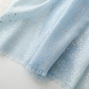 Close-up of light blue linen-feel scarf with golden sparkles and frayed edge fringe