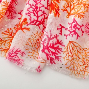 Close-up of pink coral scarf with gold foil details and natural frayed edges