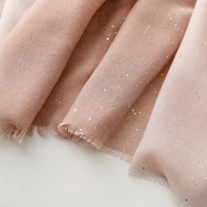 Close-up of pink linen feel scarf with gold foil accents and delicate frayed fringe edges